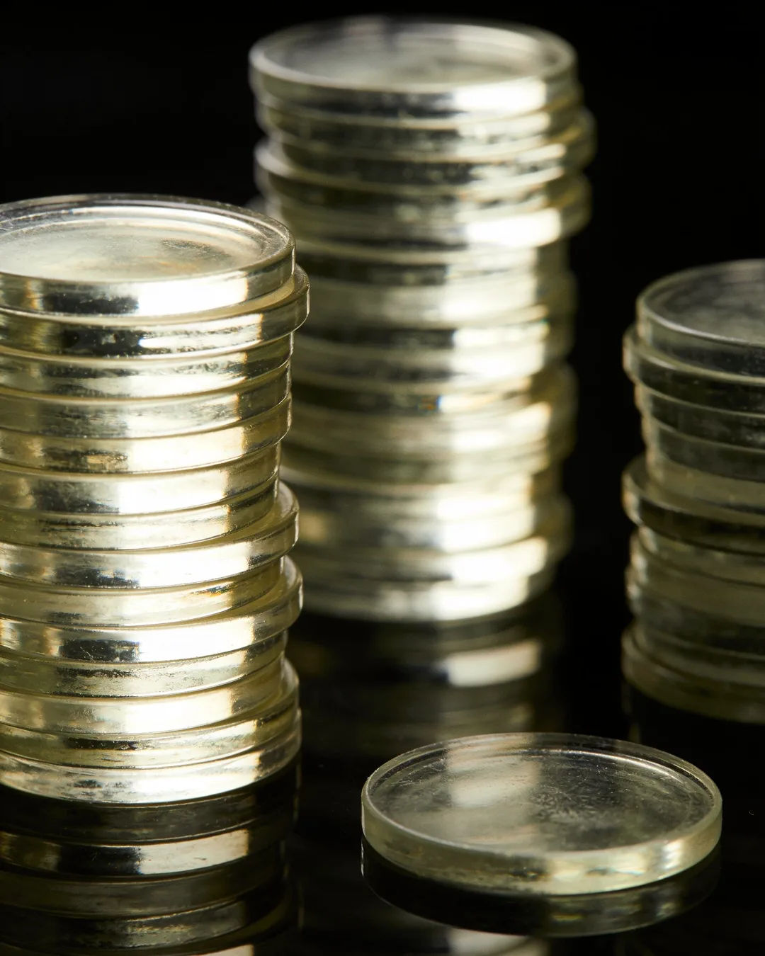 Stacks of glass tokens rising on a black ground