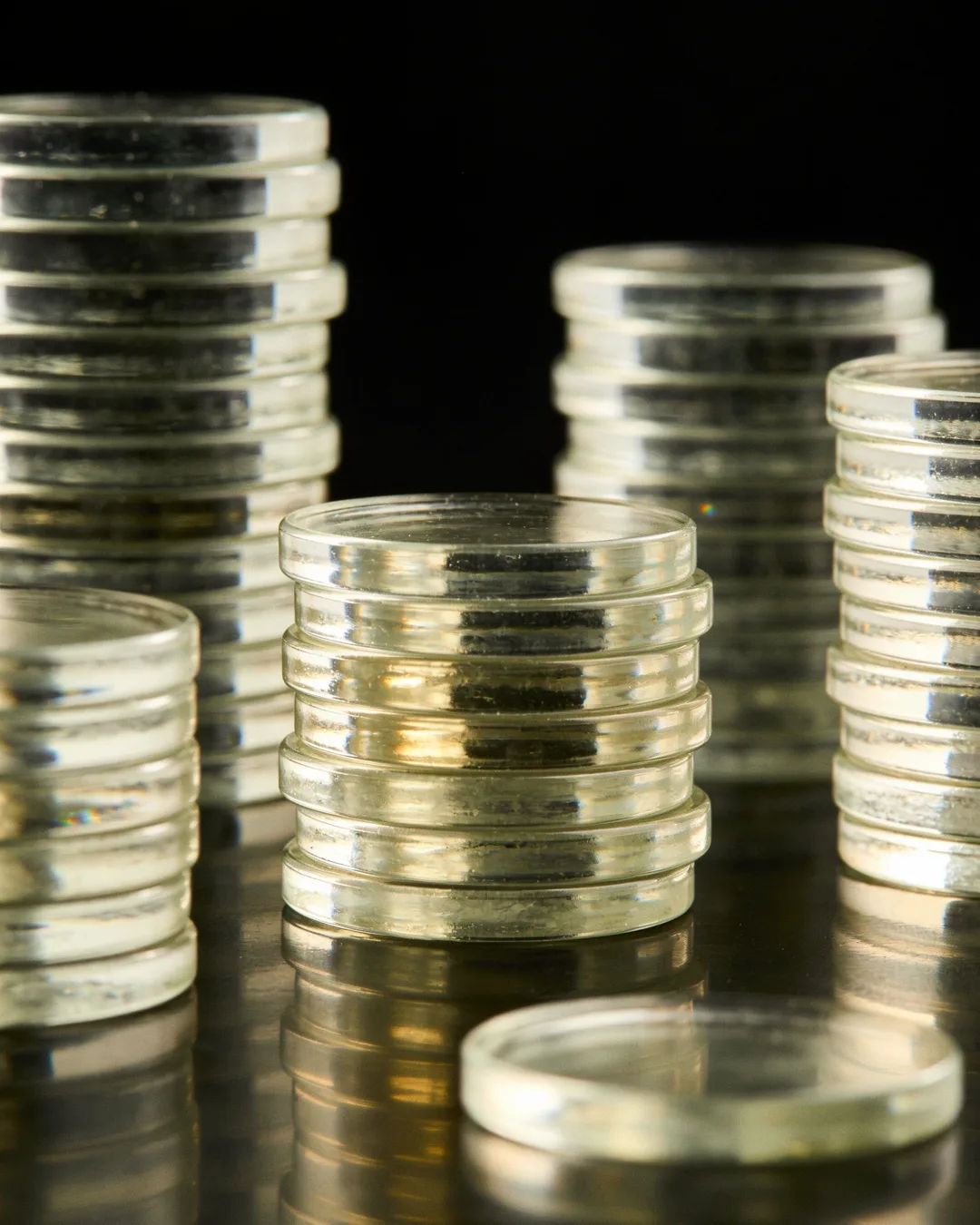Stacks of glass tokens rising on a black ground