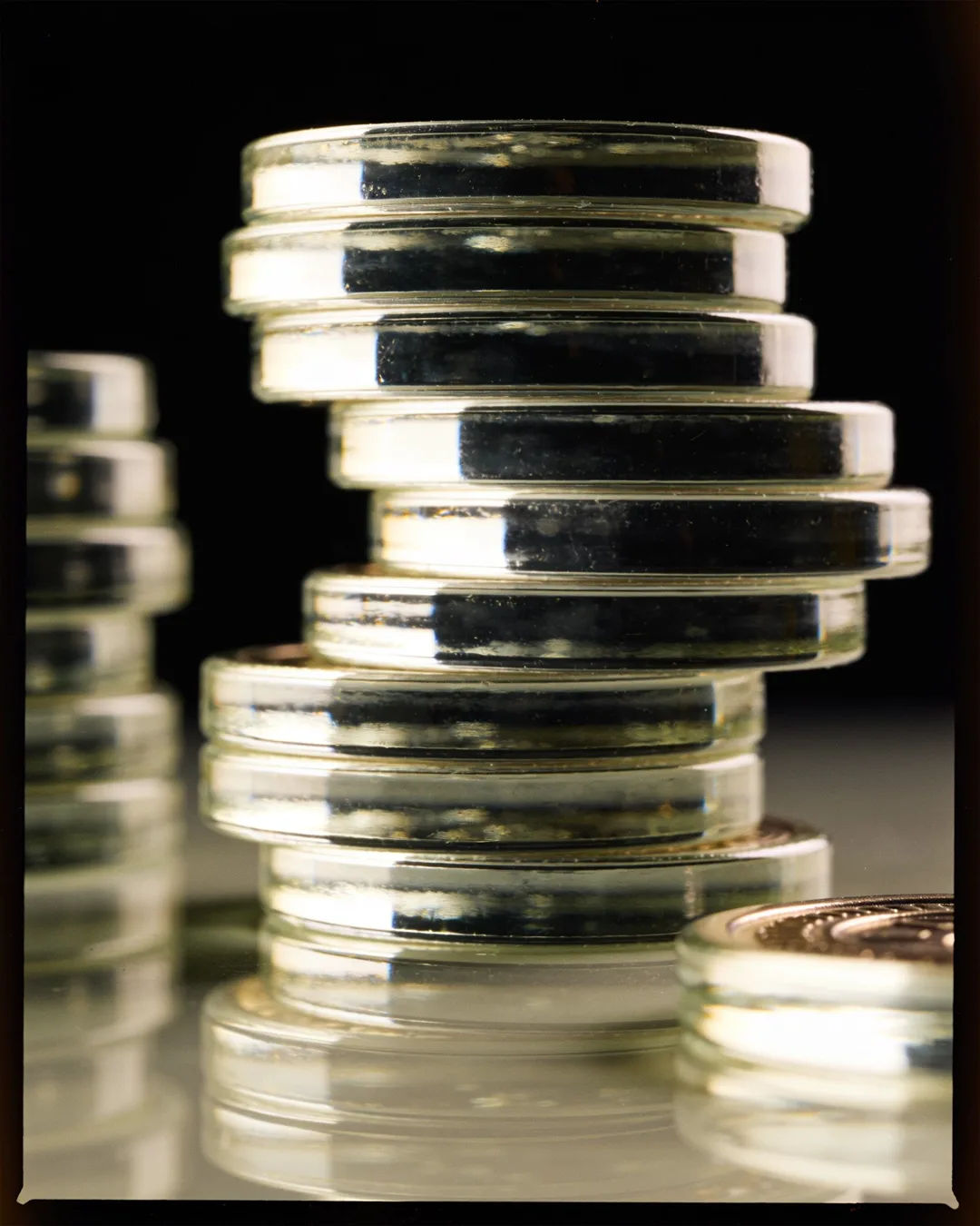 Stacks of glass tokens rising on a black ground