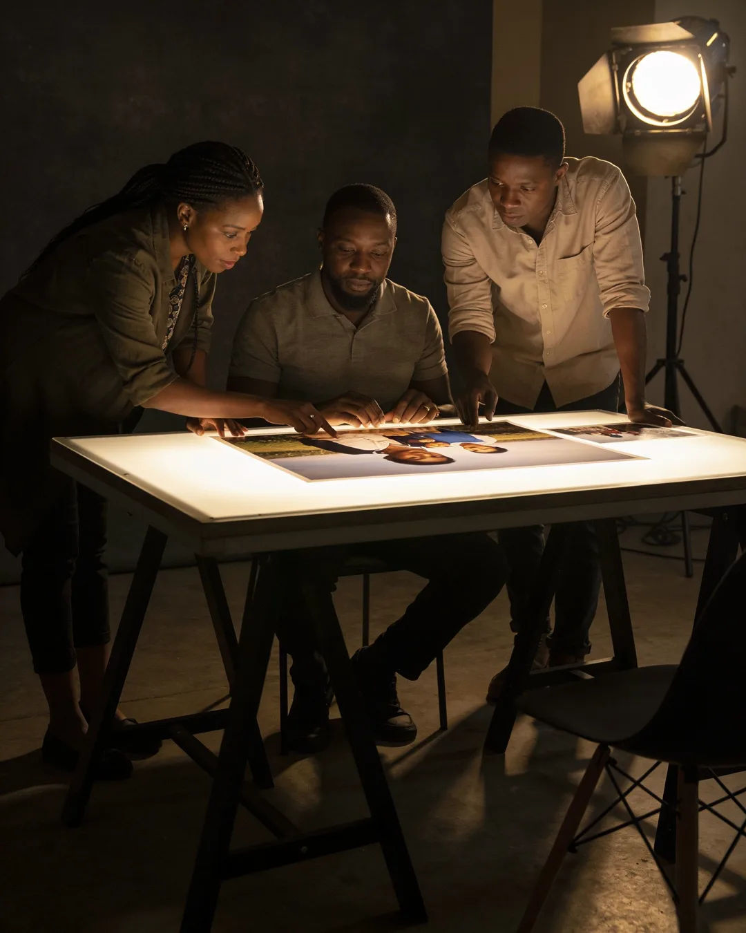 A Rwandan production team reviewing printed frames on a lit table