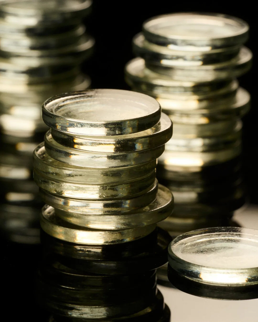 Stacks of glass tokens rising on a black ground