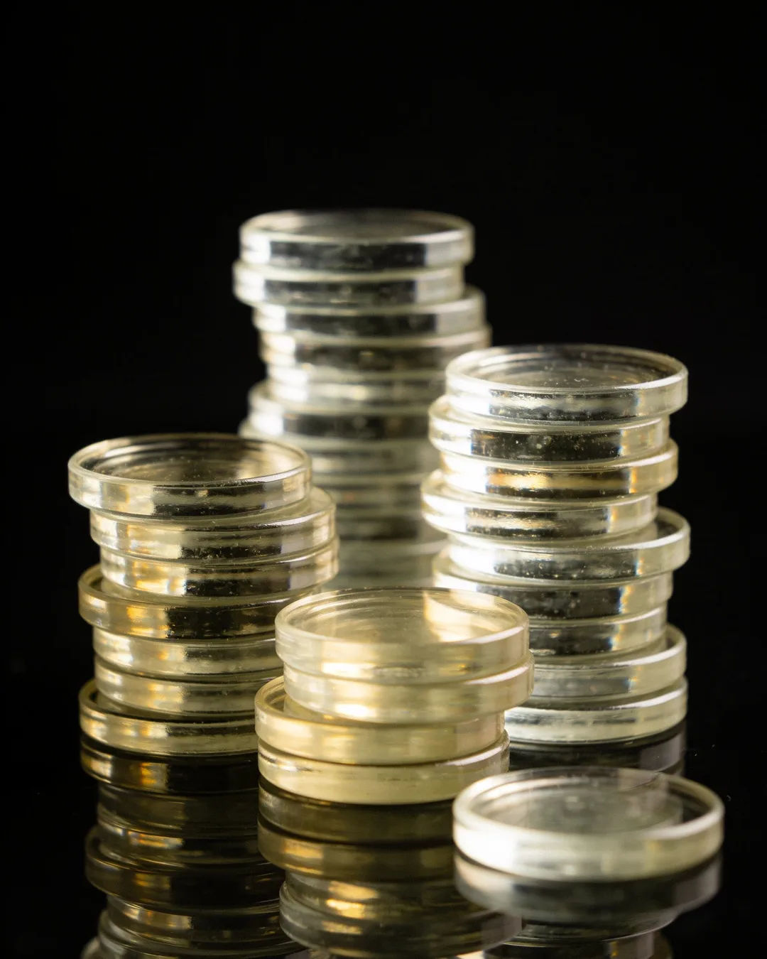 Stacks of glass tokens rising on a black ground
