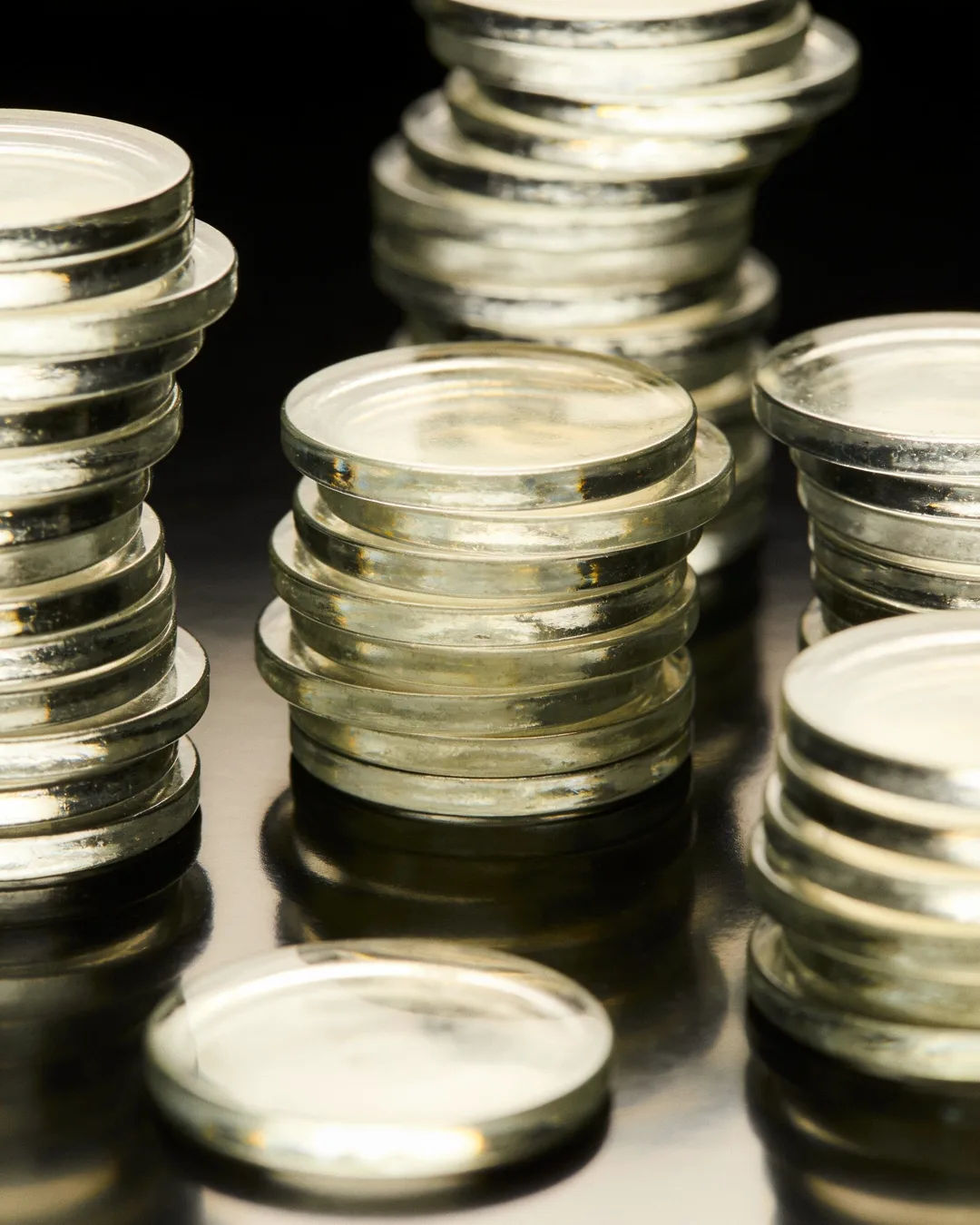 Stacks of glass tokens rising on a black ground