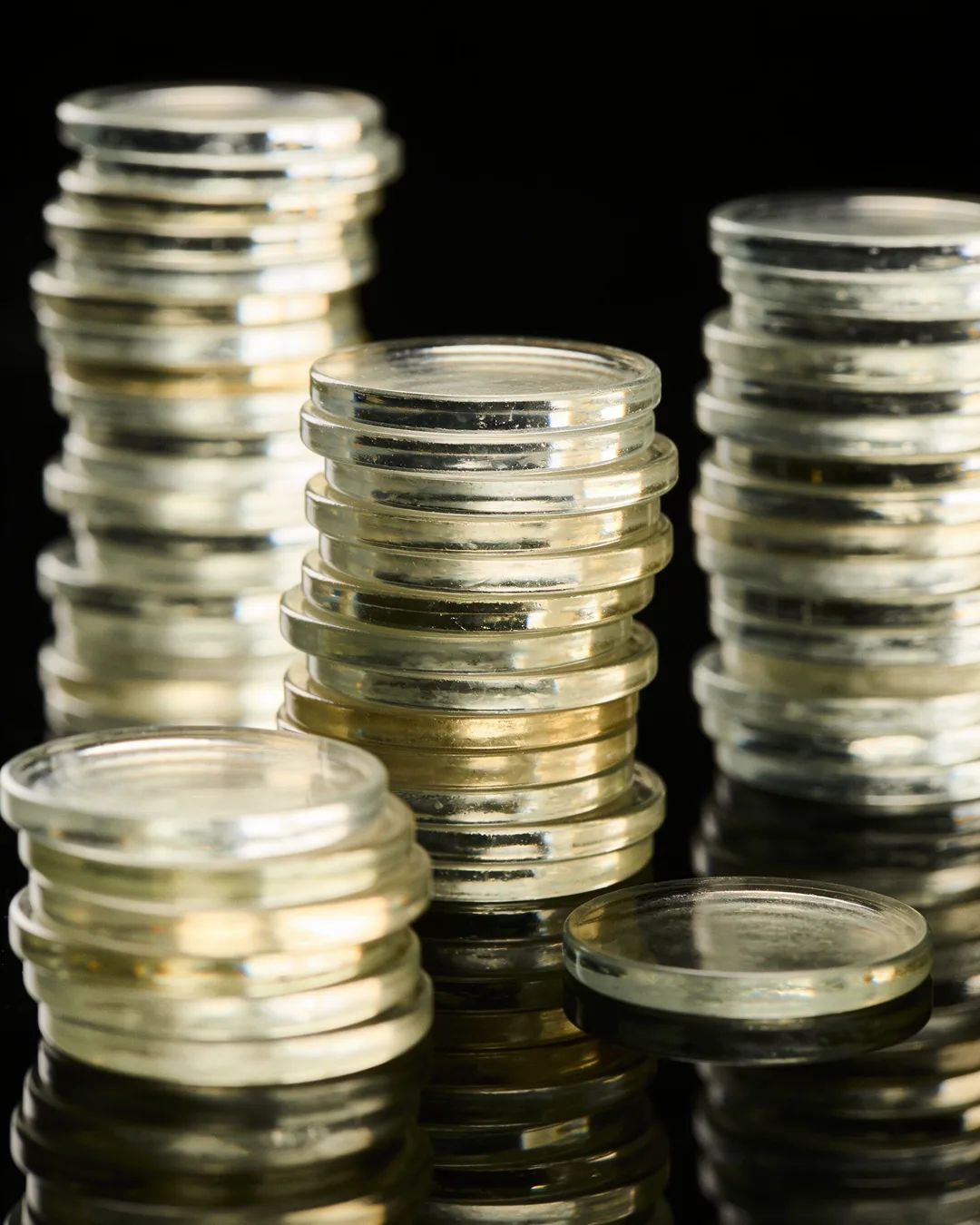 Stacks of glass tokens rising on a black ground