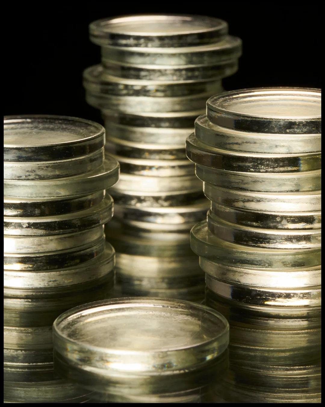 Stacks of glass tokens rising on a black ground