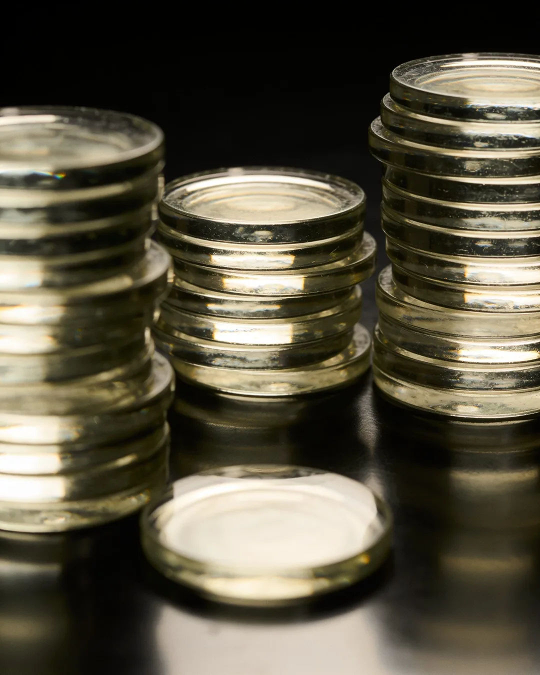 Stacks of glass tokens rising on a black ground