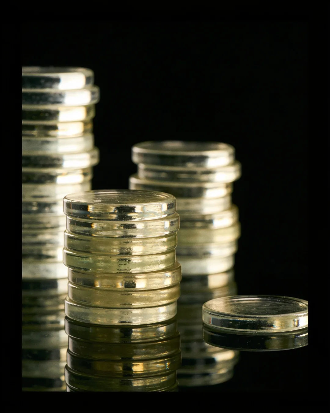 Stacks of glass tokens rising on a black ground