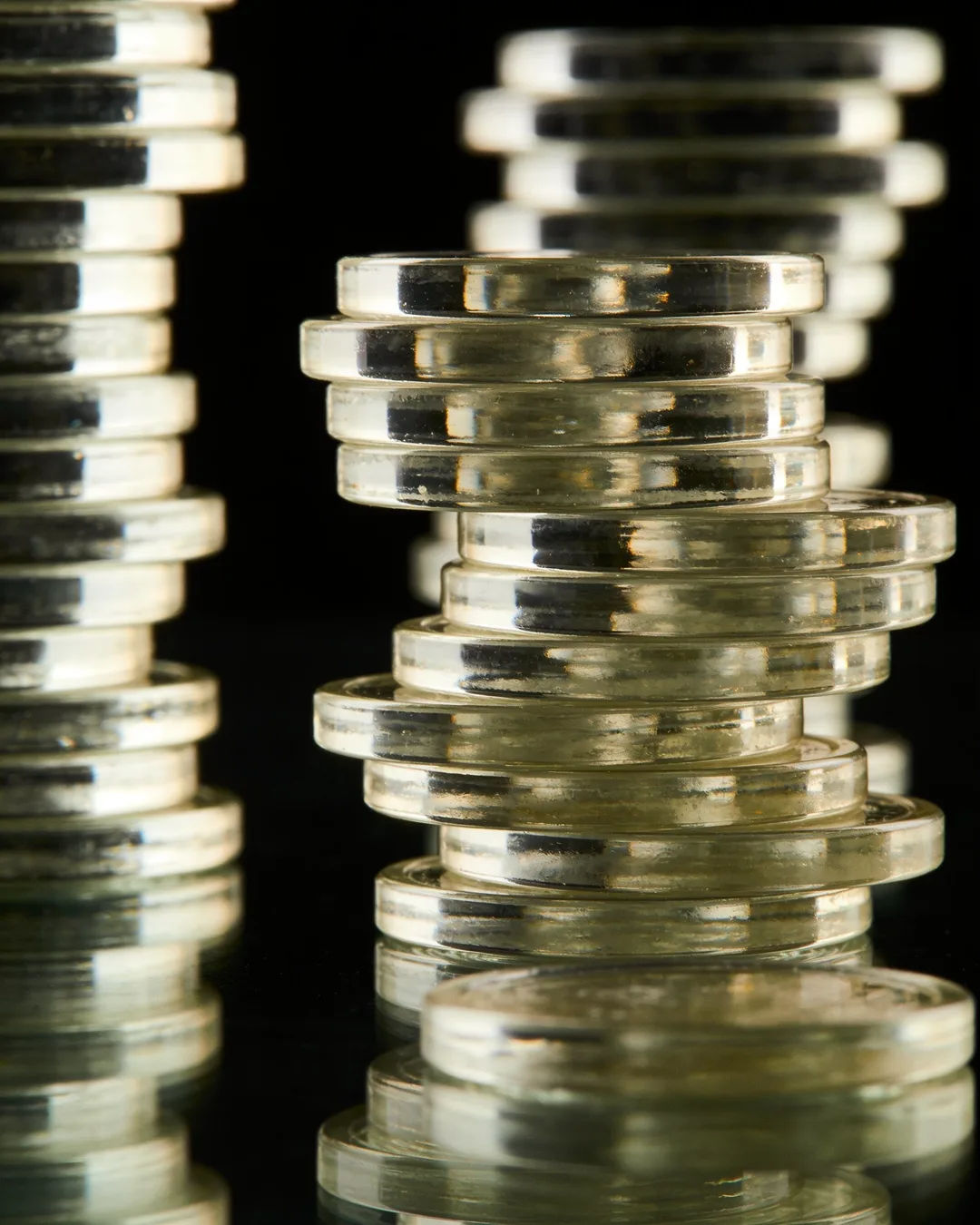 Stacks of glass tokens rising on a black ground