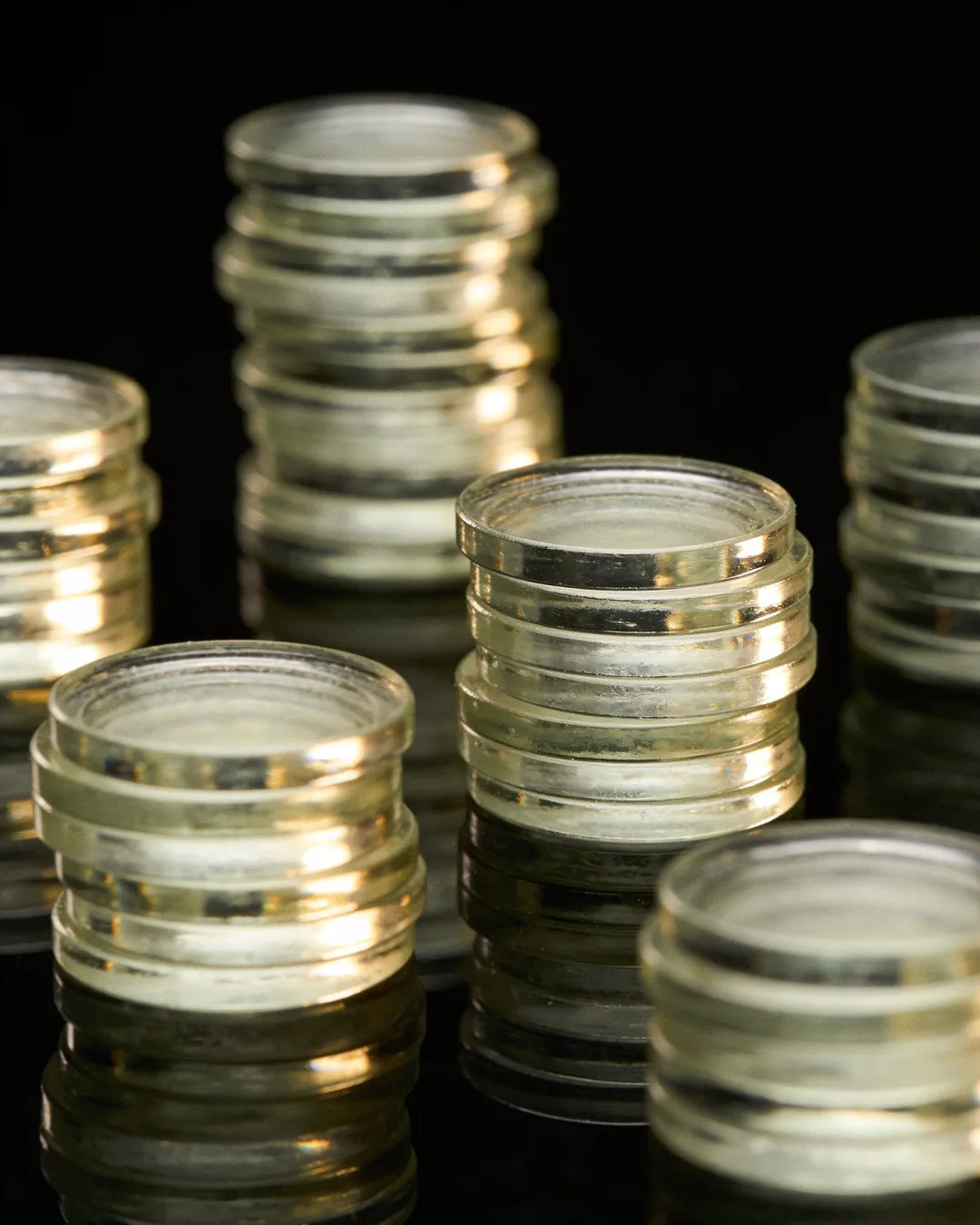Stacks of glass tokens rising on a black ground