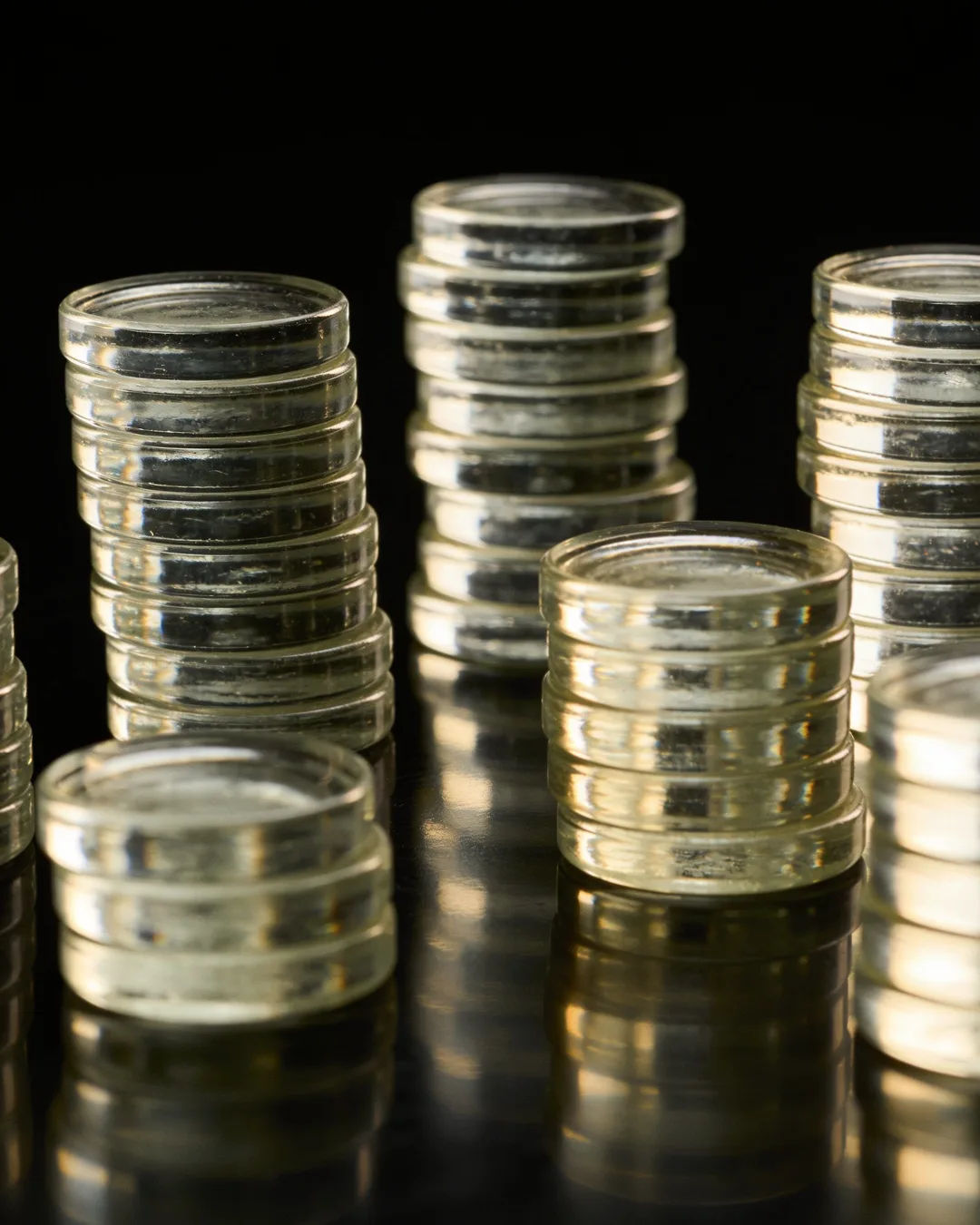 Stacks of glass tokens rising on a black ground