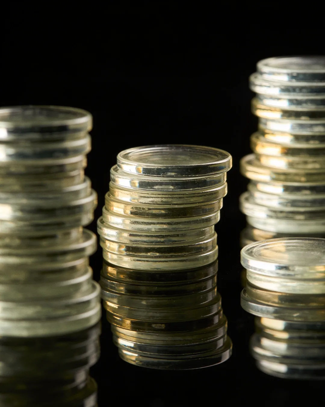 Stacks of glass tokens rising on a black ground