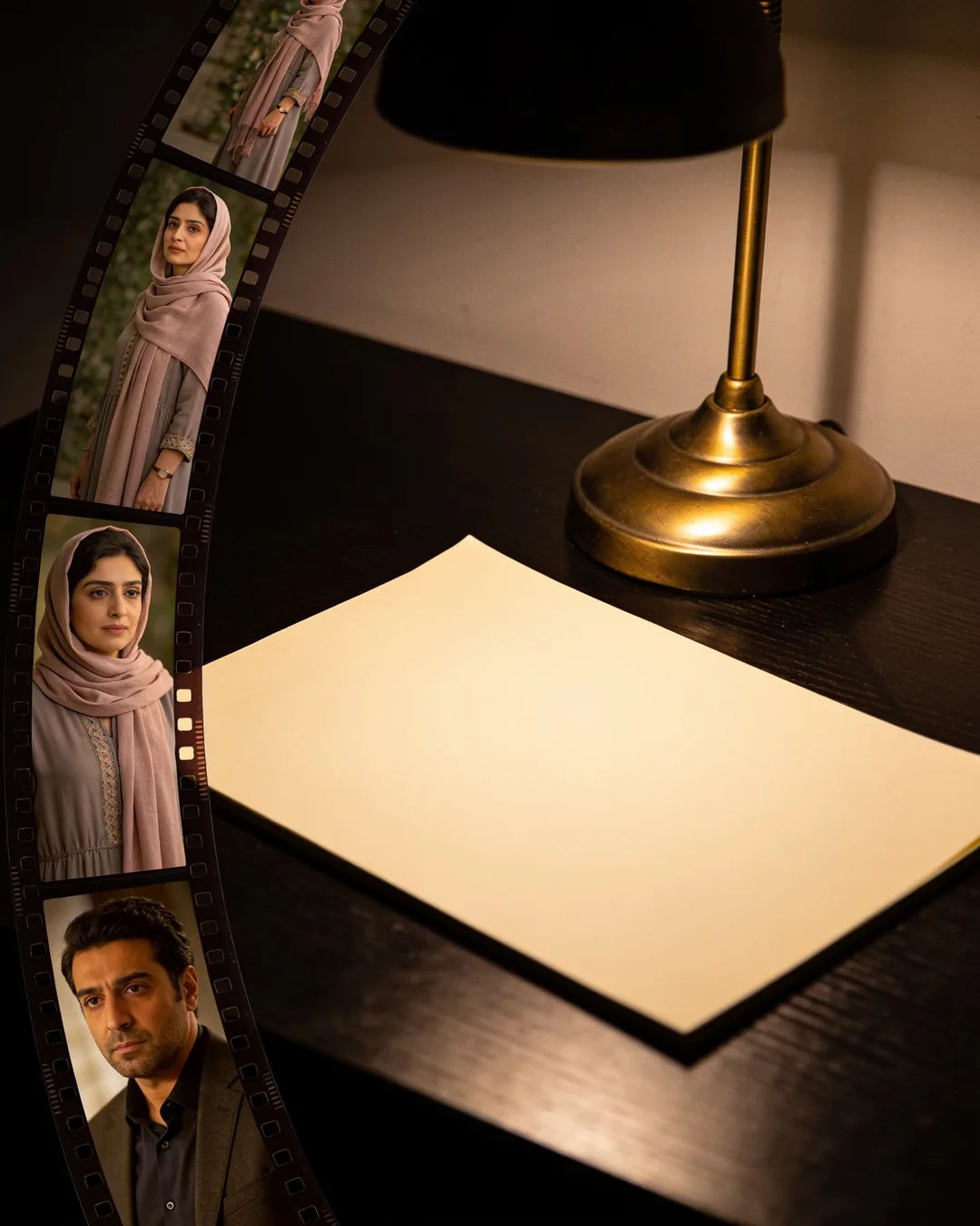 A blank page under a desk lamp beside a strip of film frames from an Iranian family drama