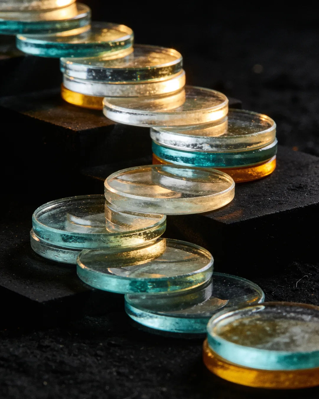 Stacks of glass tokens rising on a black ground