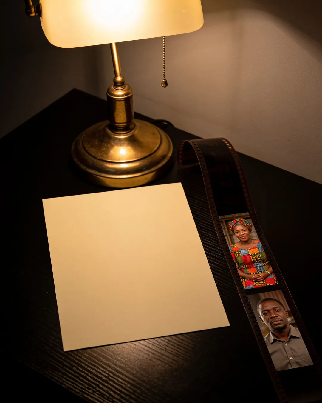 A blank page under a desk lamp beside a strip of film frames from an East African family drama