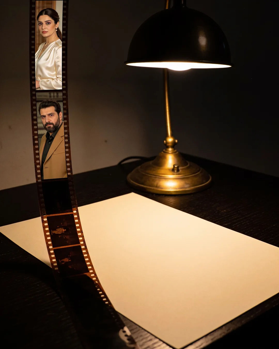 A blank page under a desk lamp beside a strip of film frames from a Turkish family drama