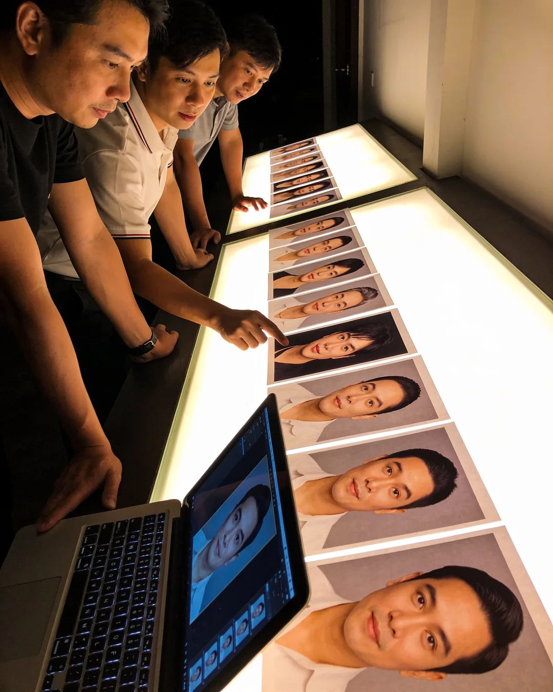 A Vietnamese production team reviewing printed frames on a lit table