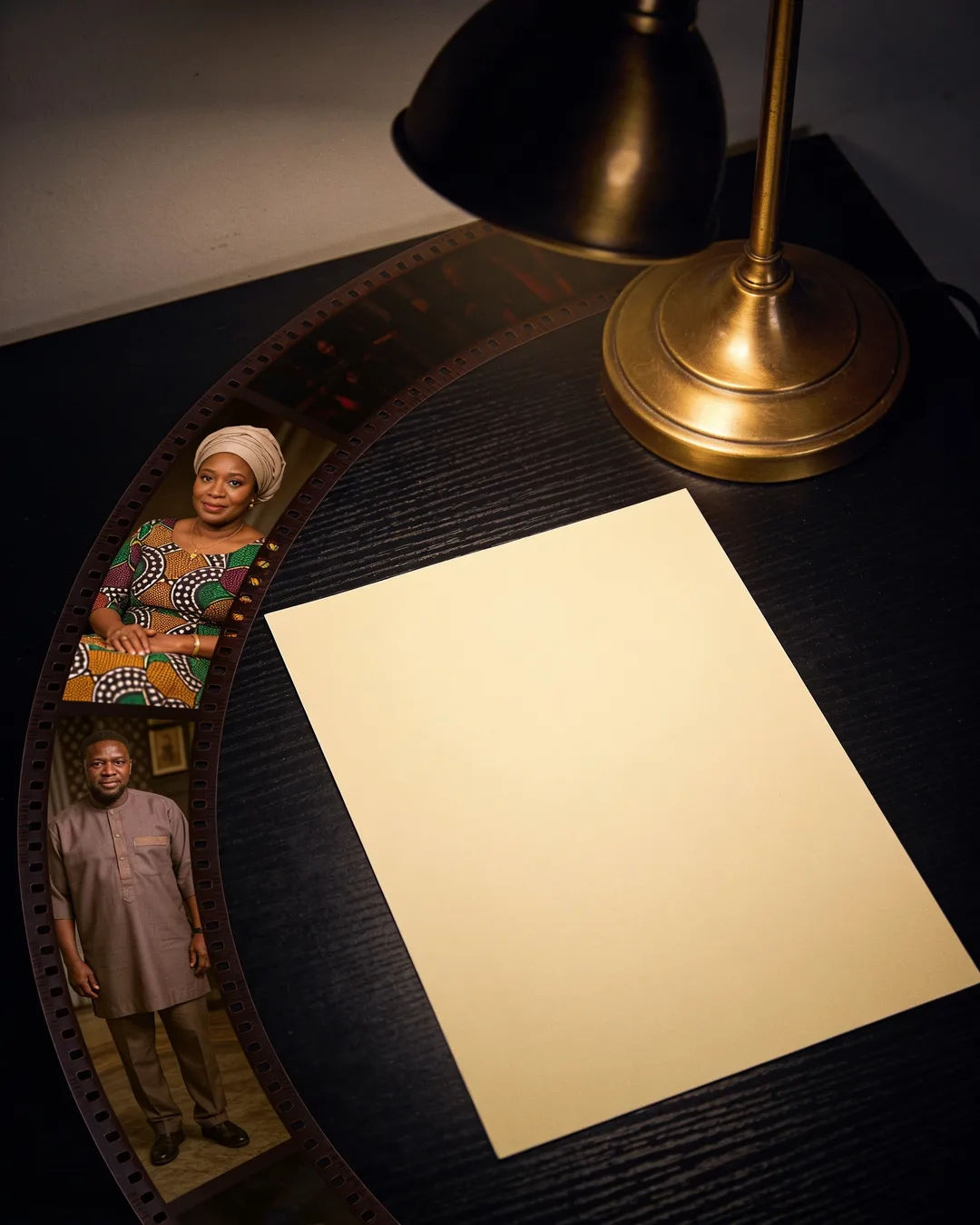 A blank page under a desk lamp beside a strip of film frames from a Yoruba family drama