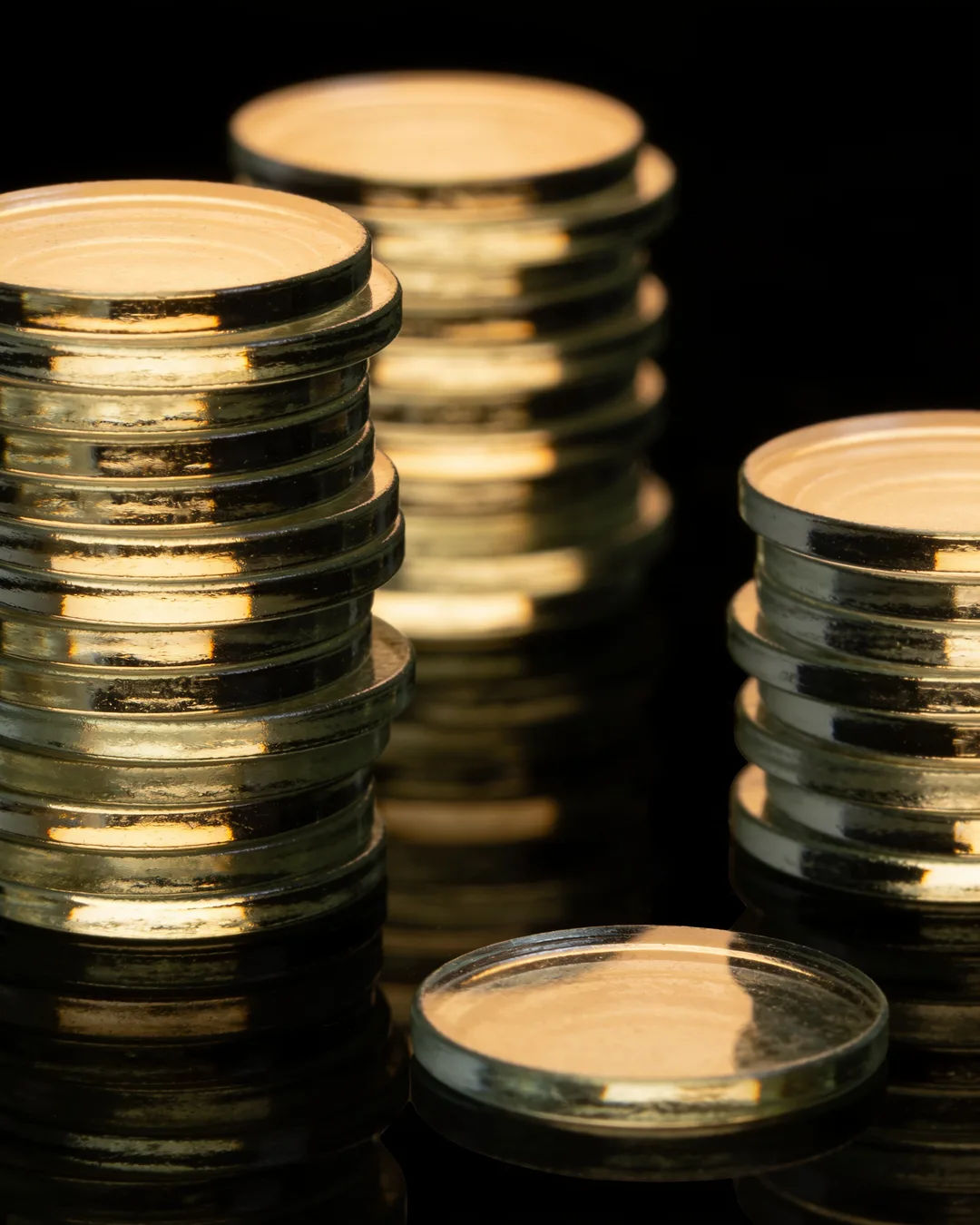 Stacks of glass tokens rising on a black ground