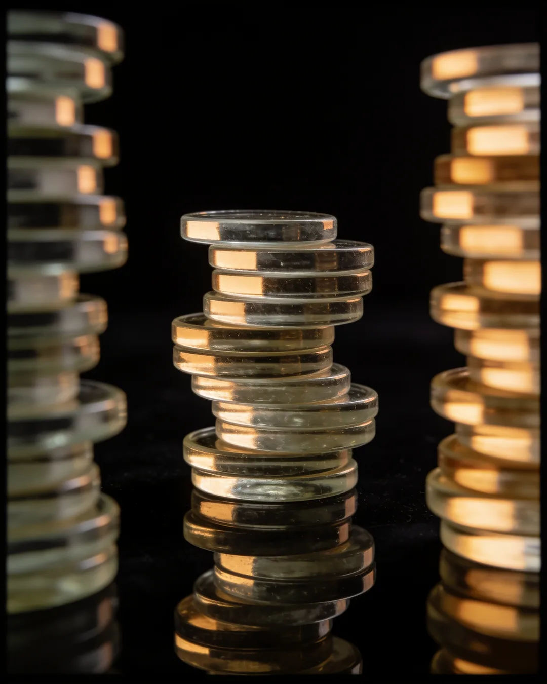 Stacks of glass tokens rising on a black ground