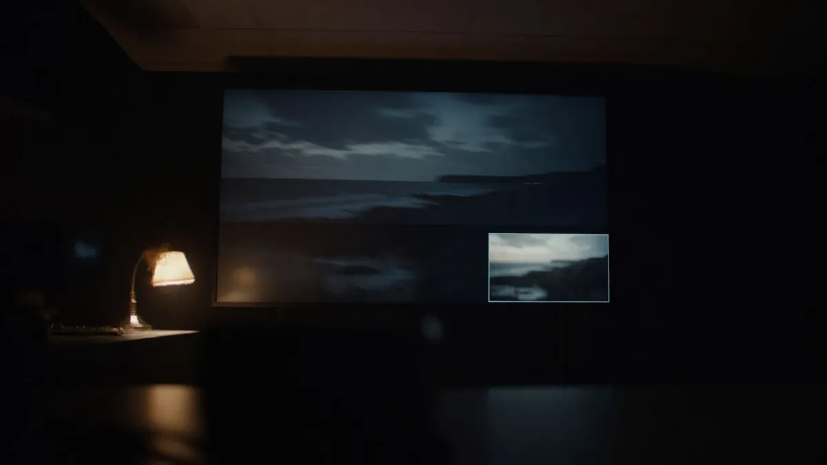 A dark visual effects studio, a large display showing a landscape composite beside a warm desk lamp