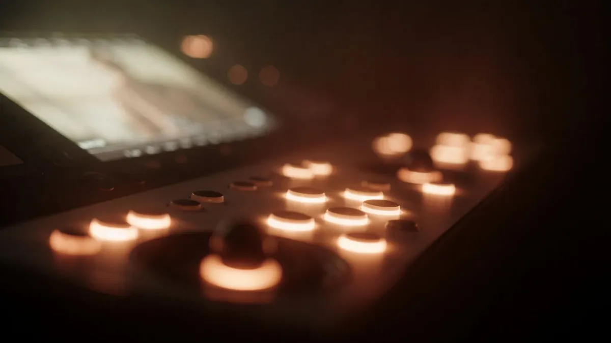 A colour grading control panel at night, illuminated trackballs glowing warm against a dark suite
