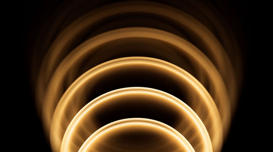 Konzentrische Bögen aus goldenem Licht, die sich wie ein angeschlagener Akkord ausdehnen