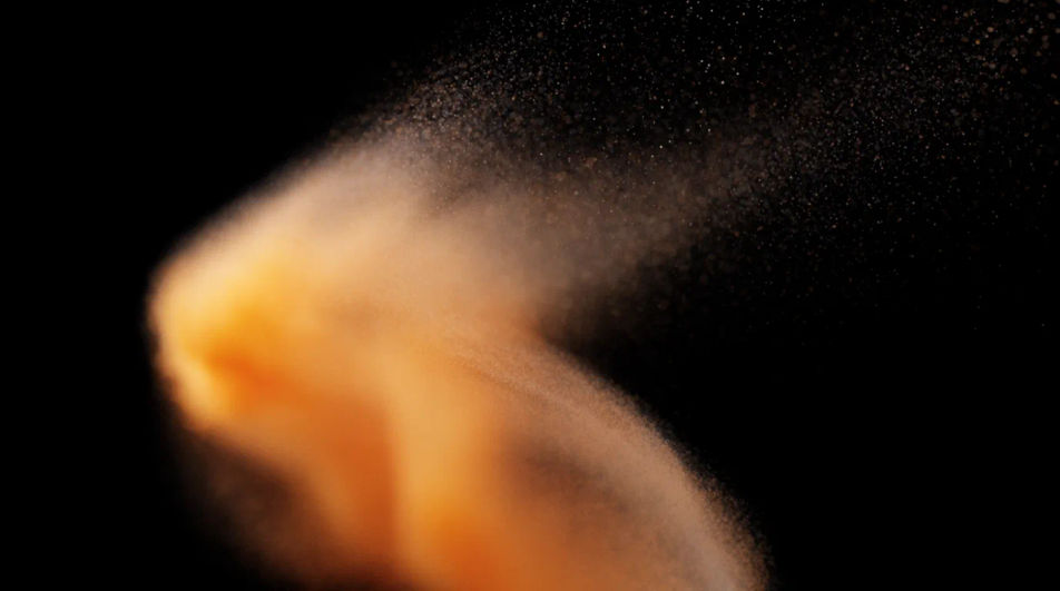 A slow drift of amber light particles curving like a page being turned against black