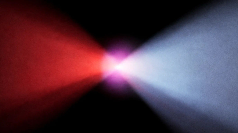 A crimson beam and a pale blue beam meeting in haze and flaring where they cross