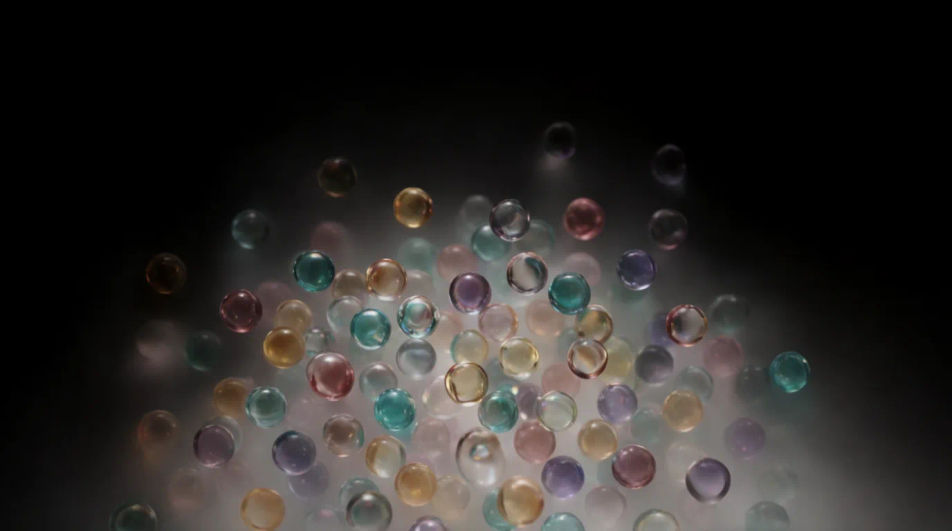 A loose cluster of small glass spheres glowing in amber, teal, rose and violet