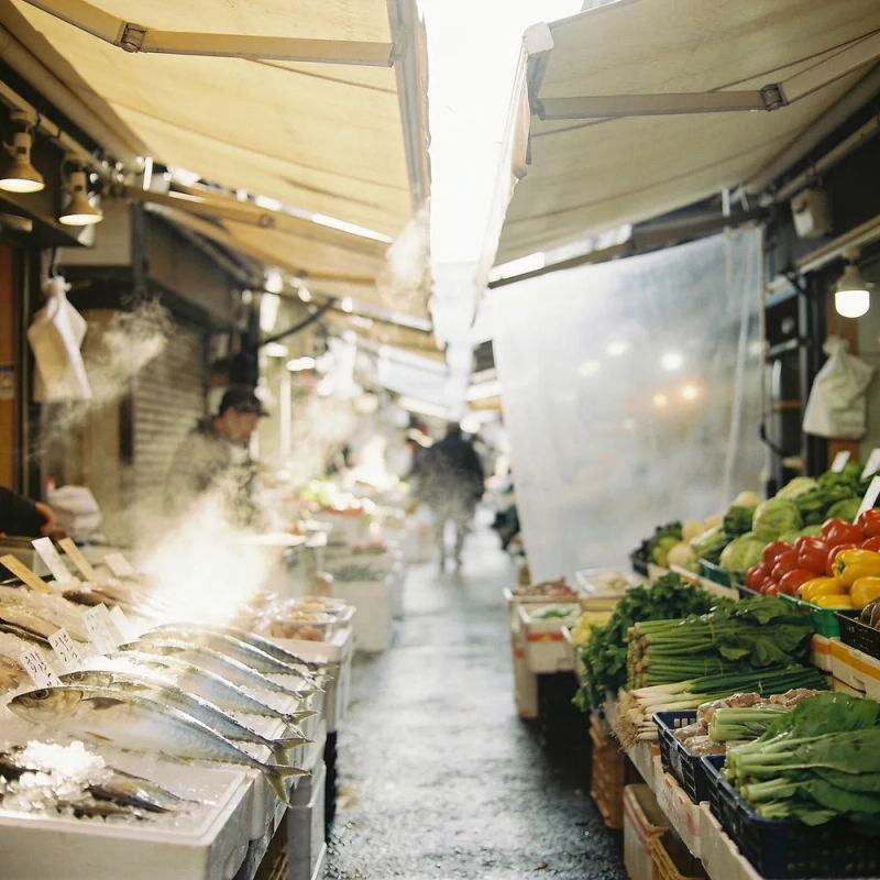 Eine schmale Marktgasse am Morgen, Dampf steigt von den Essensständen auf