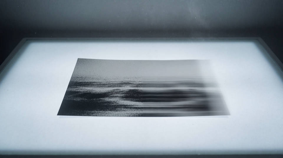 Un tirage photographique sur une table rétroéclairée, son bord droit se dissolvant en traînées horizontales