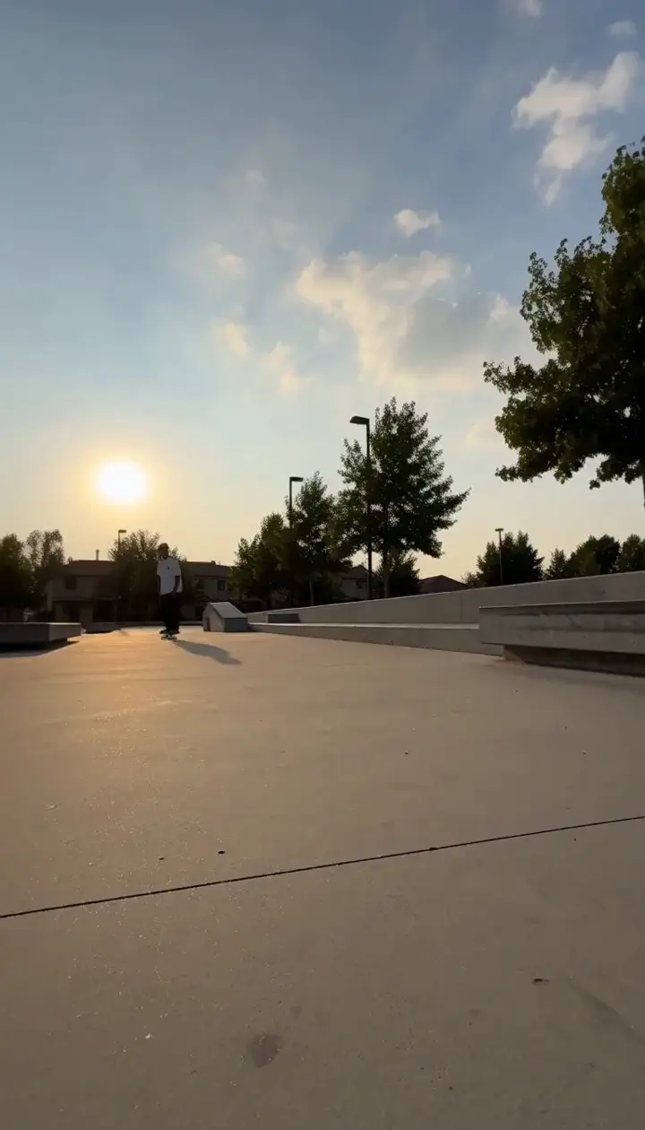 A skateboarder grinding a concrete ledge in a sunny plaza