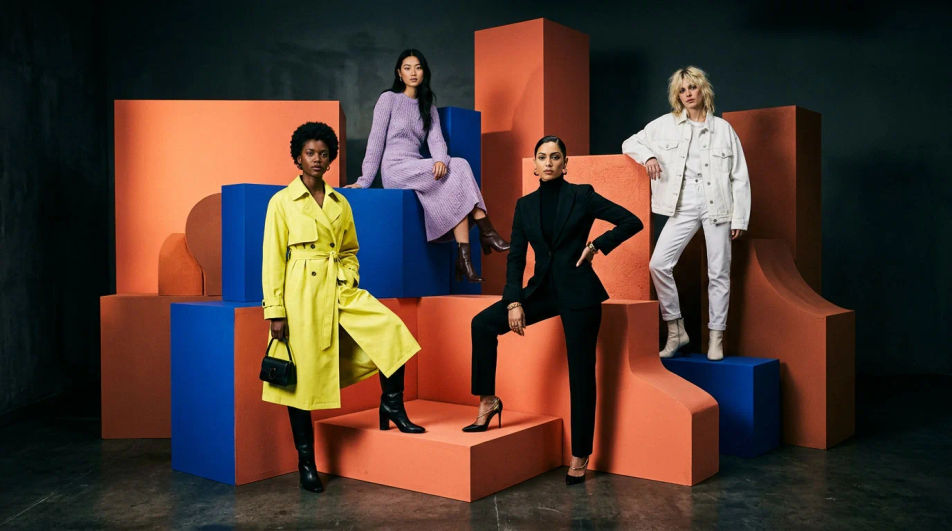 Four models in distinct outfits posing together on coral and cobalt blocks