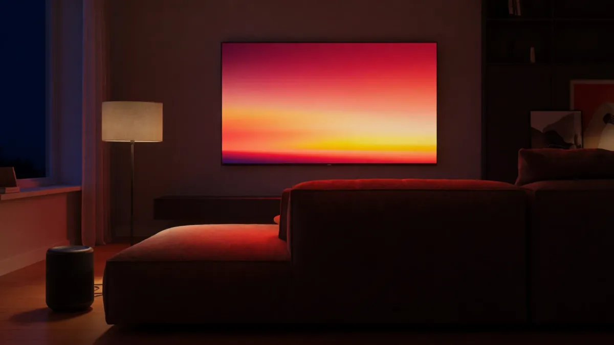 A dark living room lit only by a large television, colour spilling across the floor