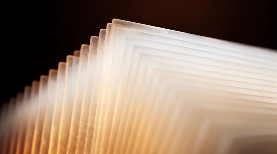 A stack of thin glass sheets glowing amber at their edges, receding like pages