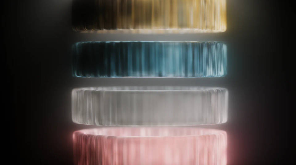 Four glowing glass strips in amber, teal, silver and rose floating apart in haze
