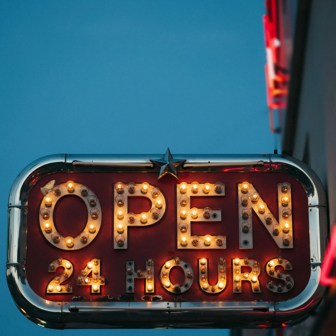 Retro diner sign spelling OPEN 24 HOURS with warm bulb lettering