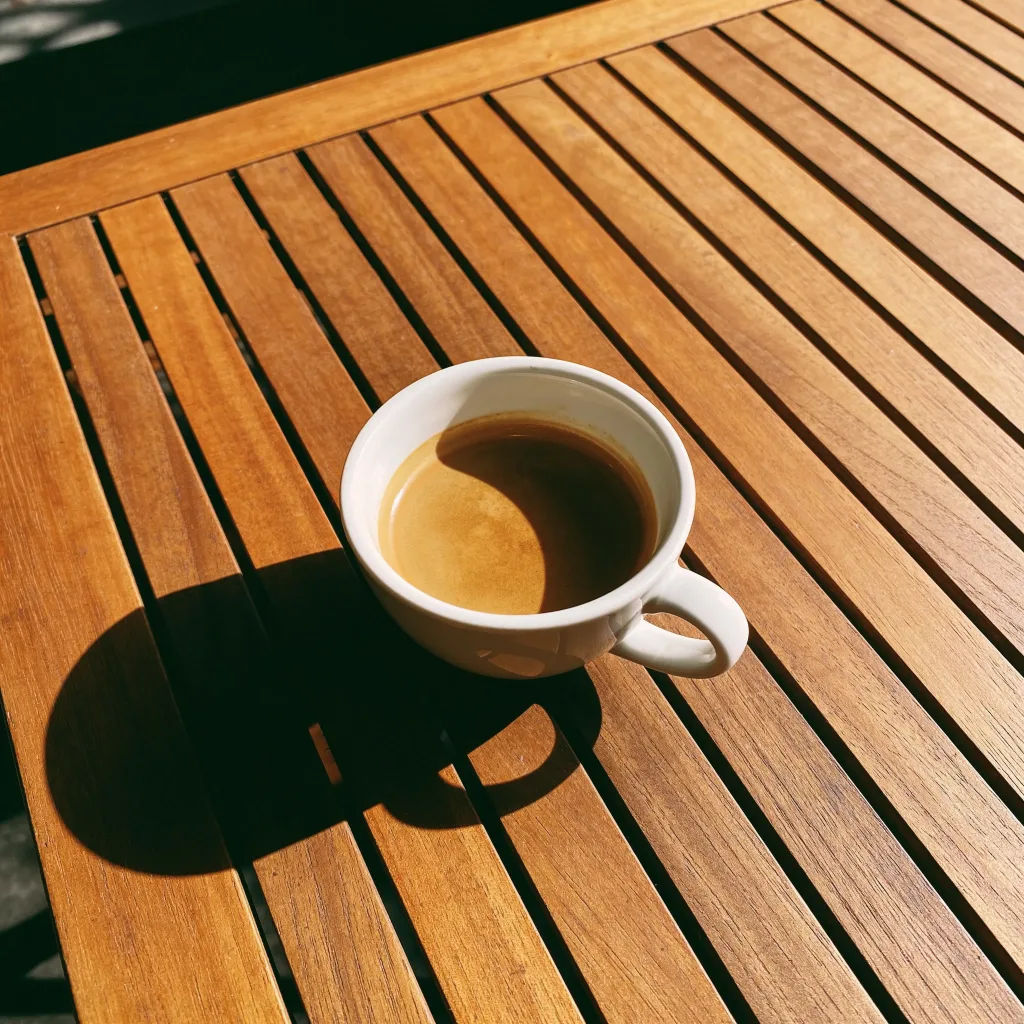Photo with a coffee cup placed on the table with natural shadow and reflection