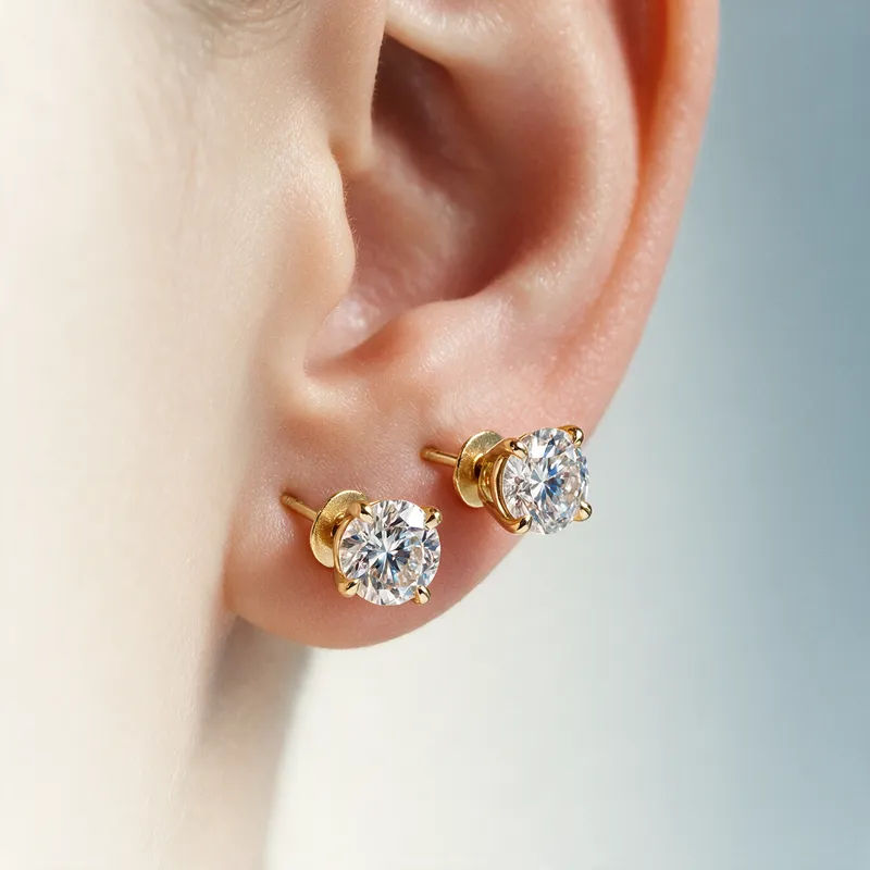 Diamond stud earrings in extreme macro with sharp facets on a soft gradient