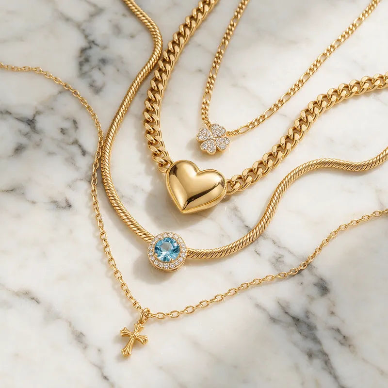 Layered gold chains in a top-down flat-lay on white marble