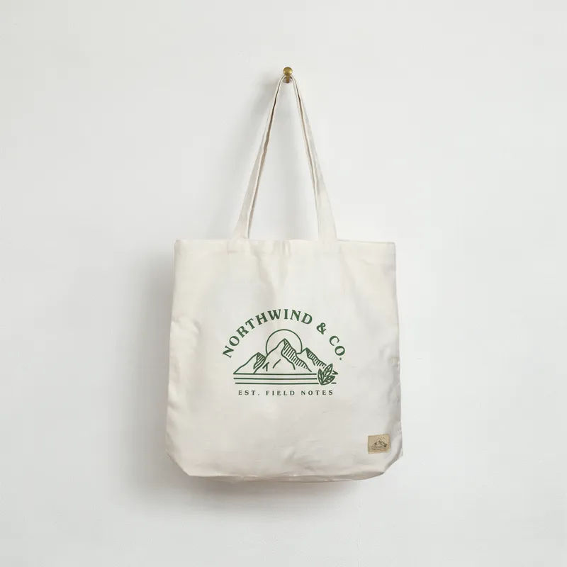 Uploaded artwork printed on a natural canvas tote bag hanging against a plain wall