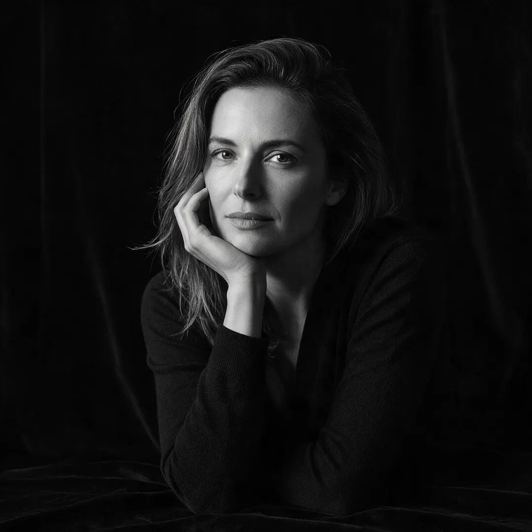 Editorial black and white portrait on a dark background with dramatic side light