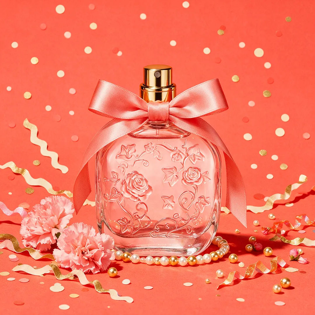 Perfume bottle on a bold coral backdrop with crisp studio light