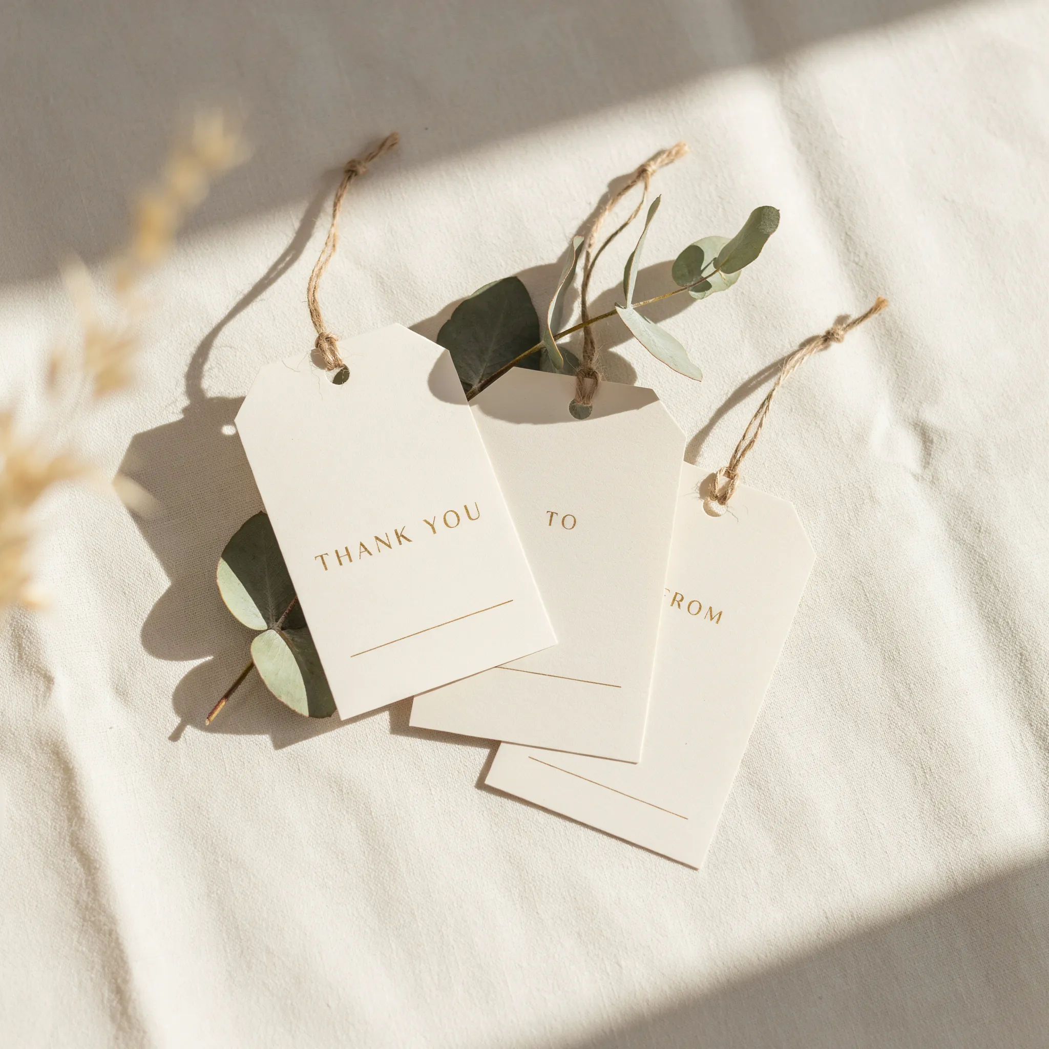Cream wedding favour tags with eucalyptus, gold accents and thank you text