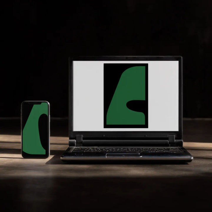 Notebook ao lado de um celular em uma mesa, com telas equivalentes