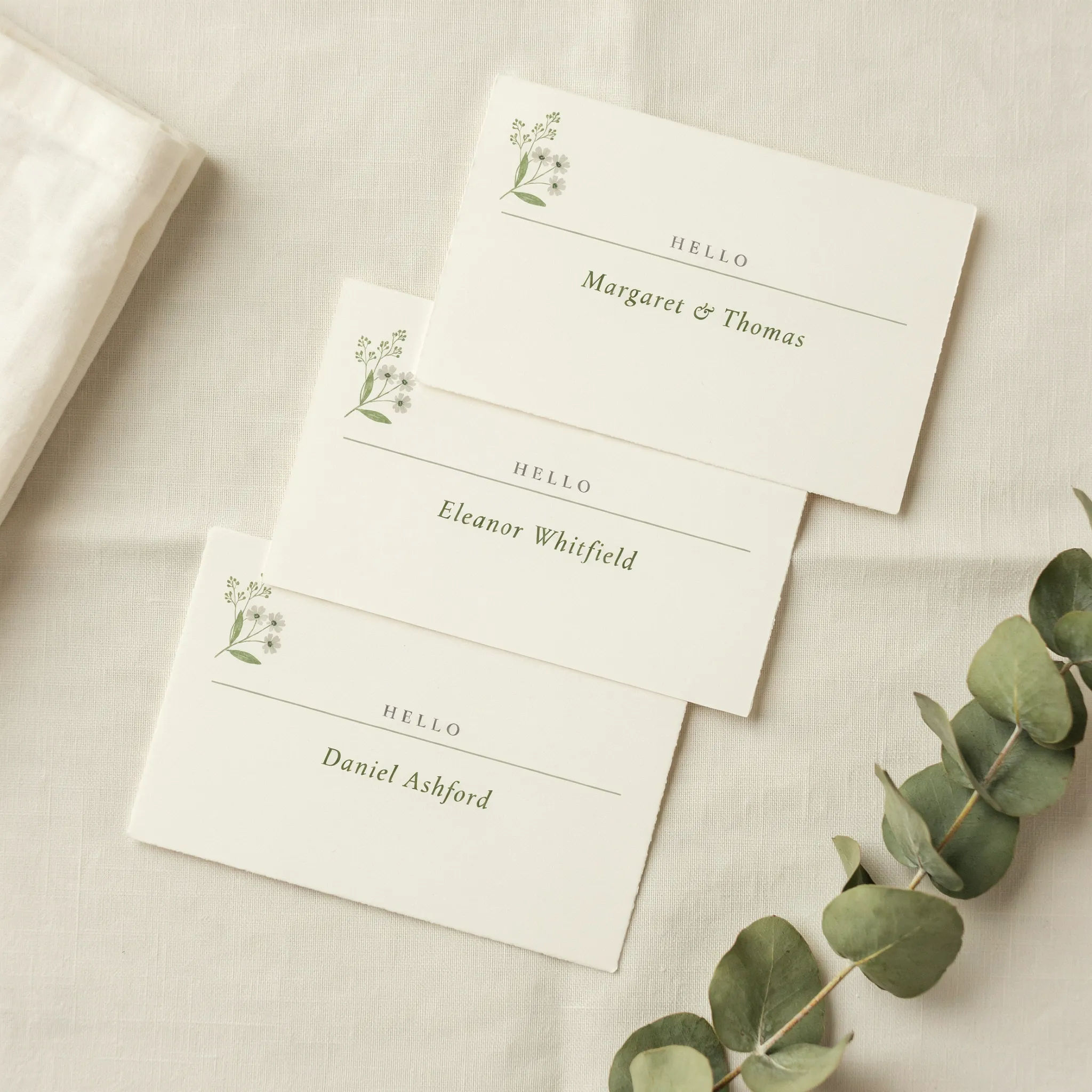 Cream and sage wedding name cards with a floral corner and clear centre