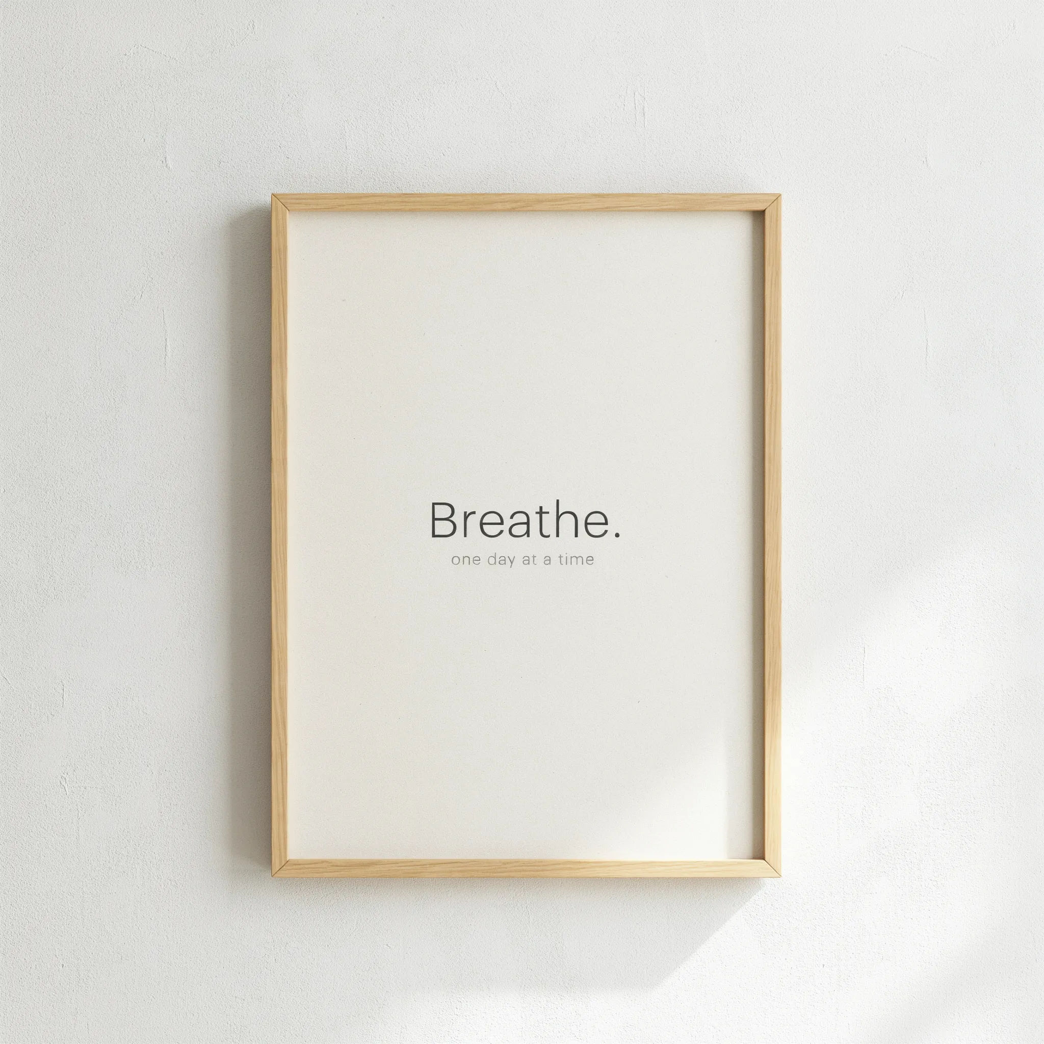 Framed minimal quote poster hanging on a plaster wall in daylight