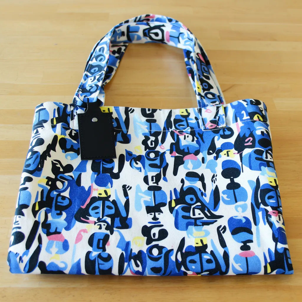 Tote bag with an edge to edge repeating pattern folded on a wood table