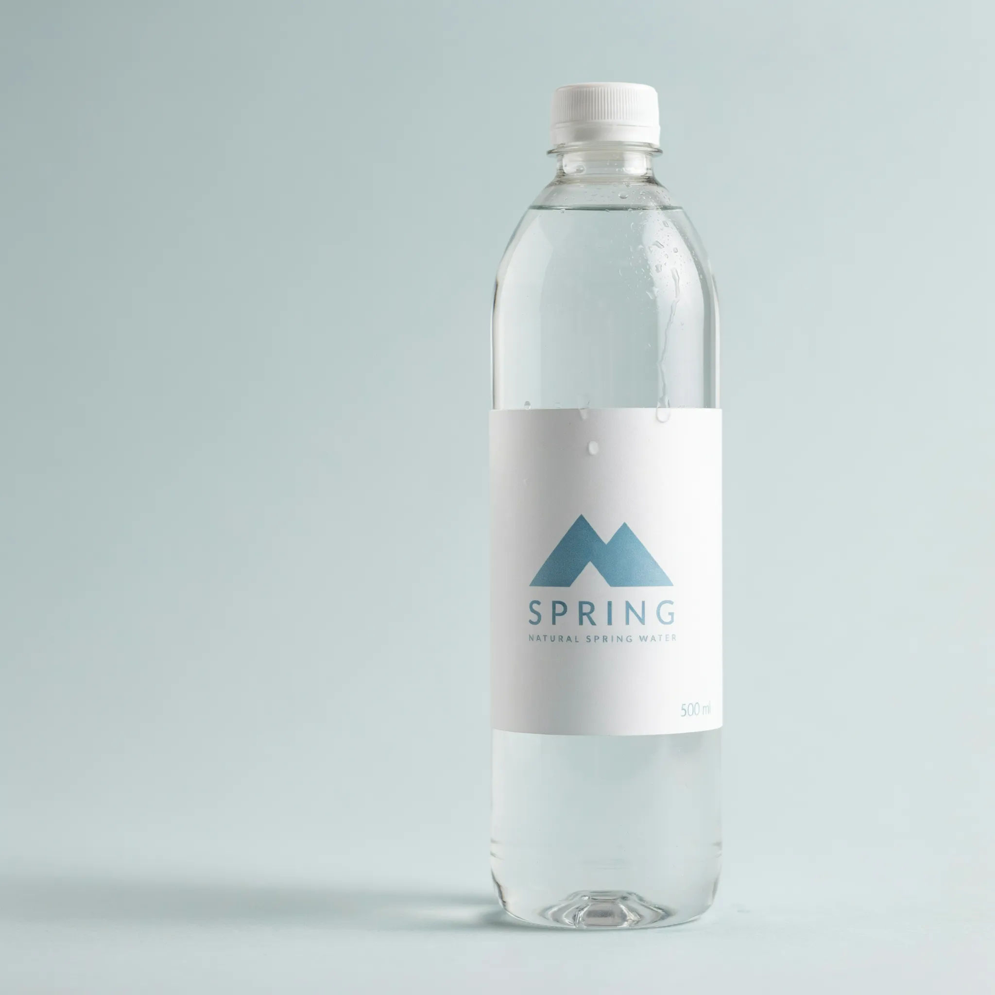 Soft blue spring water label with a mountain mark on a misted bottle