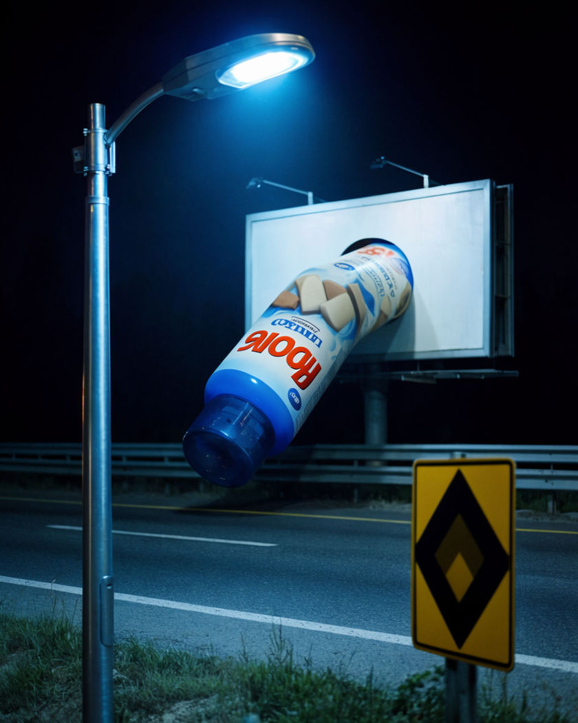 A product breaking out of a highway billboard frame and reaching over the lanes below